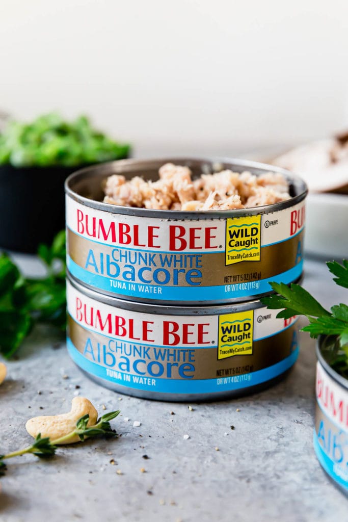 Two cans of Bumble Bee Chunk White Albacore Tuna stacked on top of one another. The top can is open to show the tuna inside. 
