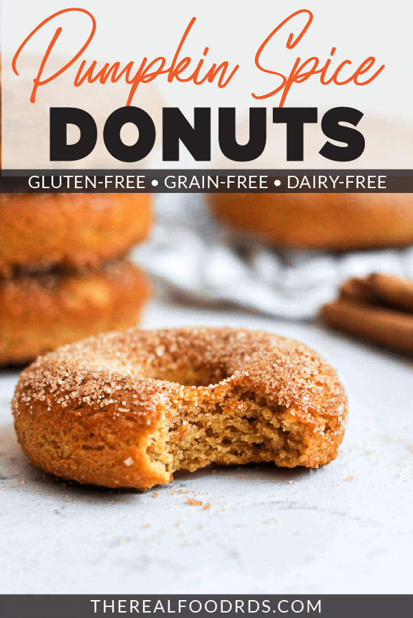 Healthy Baked Pumpkin Donuts with a bit taken out of it with a stack of three pumpkin donuts behind it.