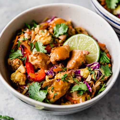 Veggie Chicken Pad Thai in a creamy bowl and topped with cashews and lime wedges.