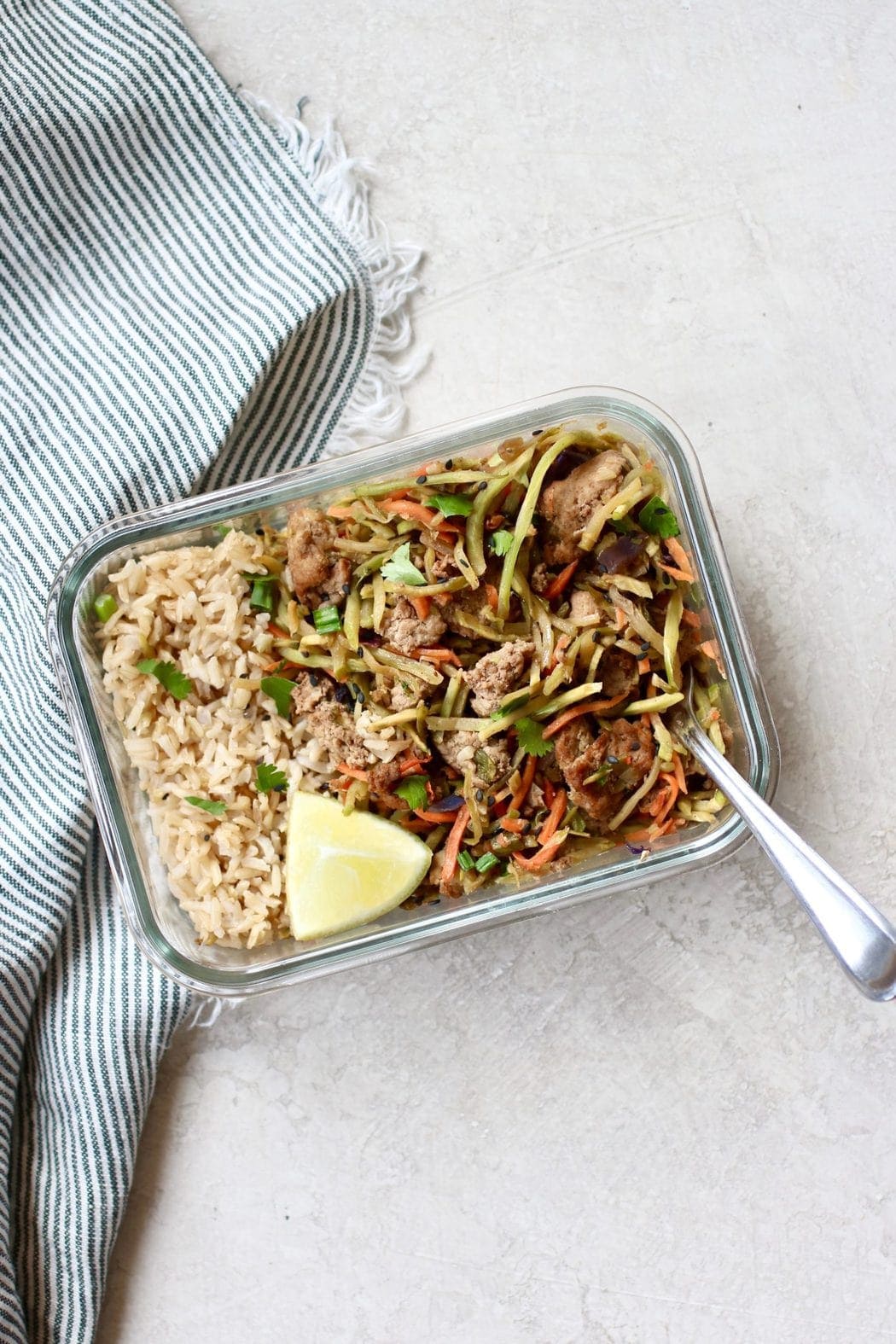 Egg roll in a bowl in a glass container with a side of rice