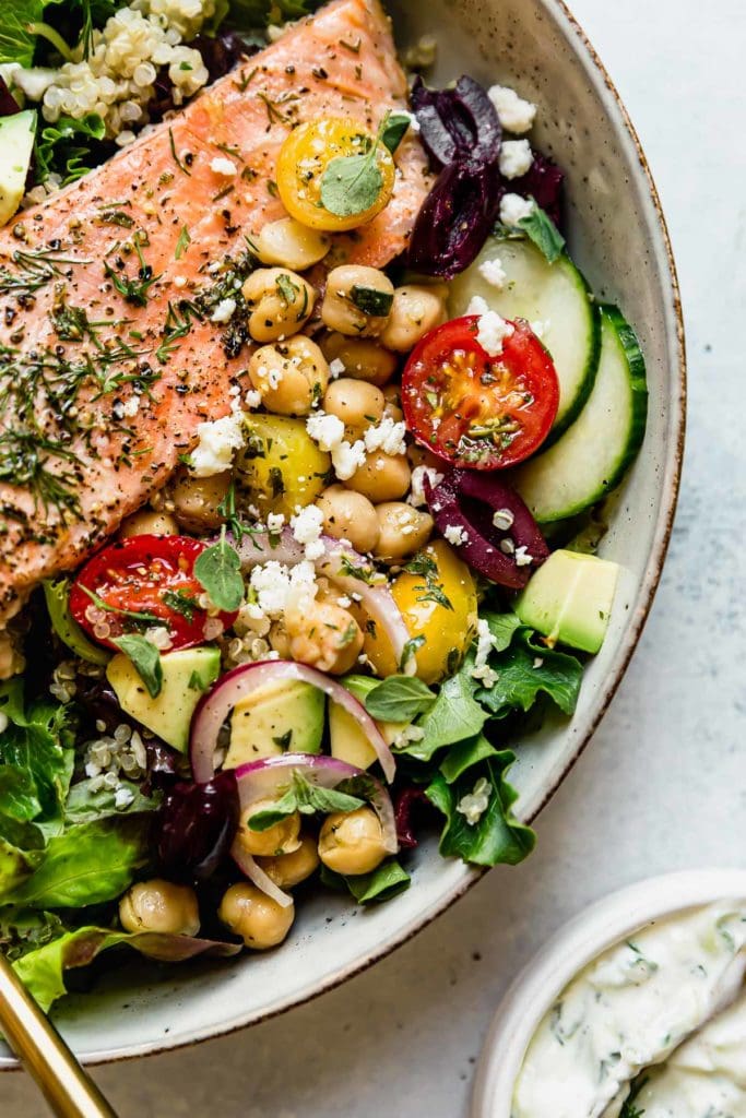 Mediterranean Bowl with Salmon in a light colored bowl with a gold fork. 