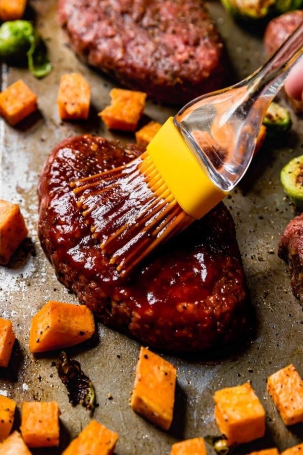 A mini meatloaf being brushed with bbq sauce
