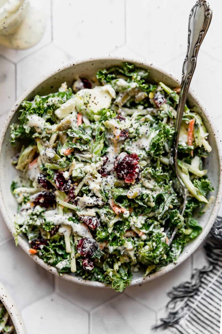 Overhead view of a bowl of sweet kale salad with a serving spoon on the right side of the dish. 