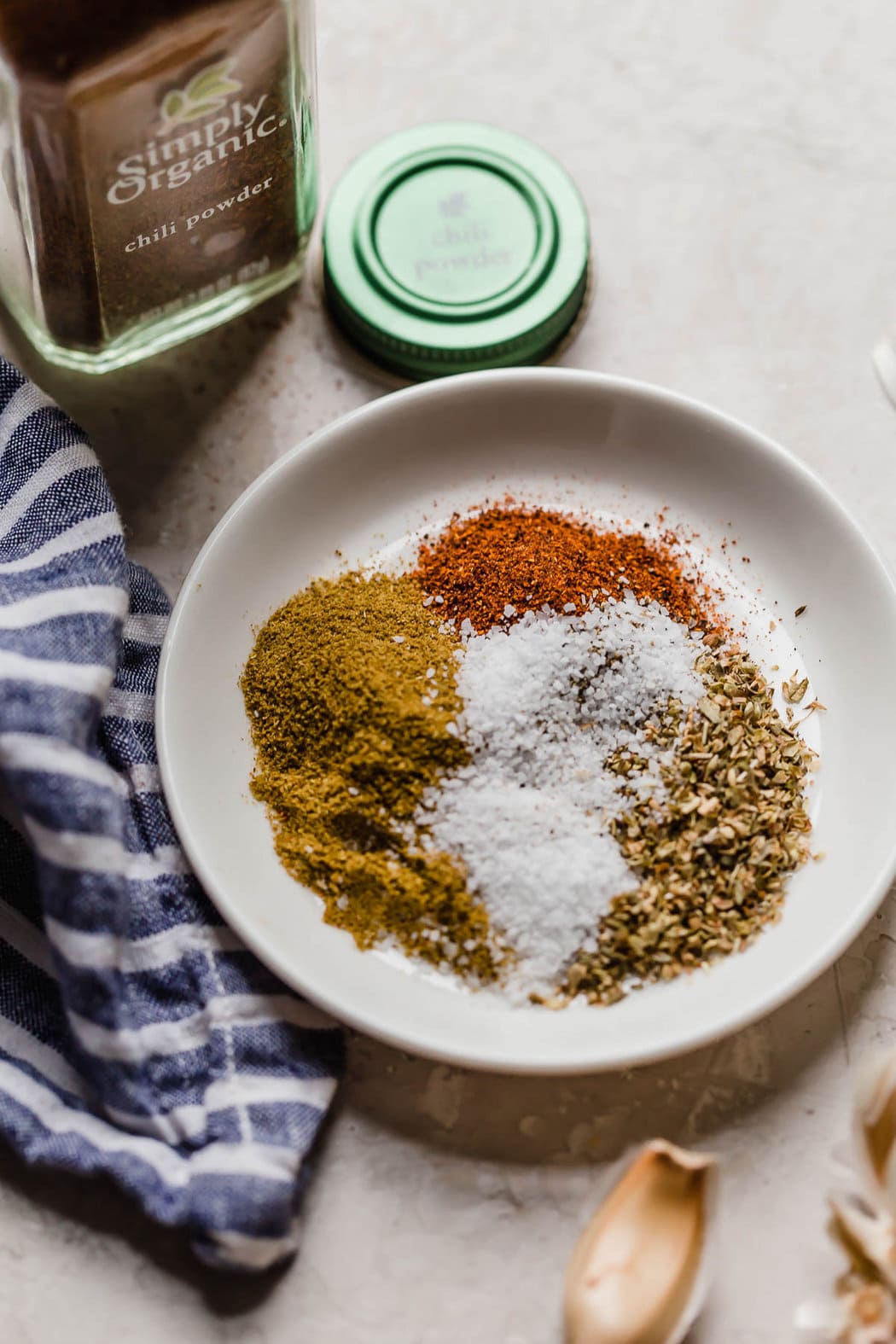 Overhead view of a variety of spices in a shallow white bowl for Slow Cooker White Chicken Chili 