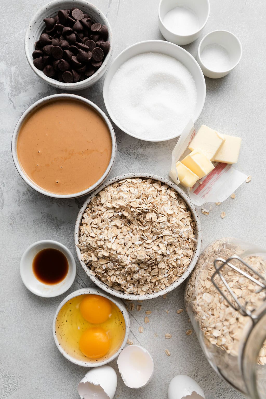 Overhead view of a variety of ingredients for Peanut Butter Oatmeal Cookies with Chocolate Chips in different sized bowls.