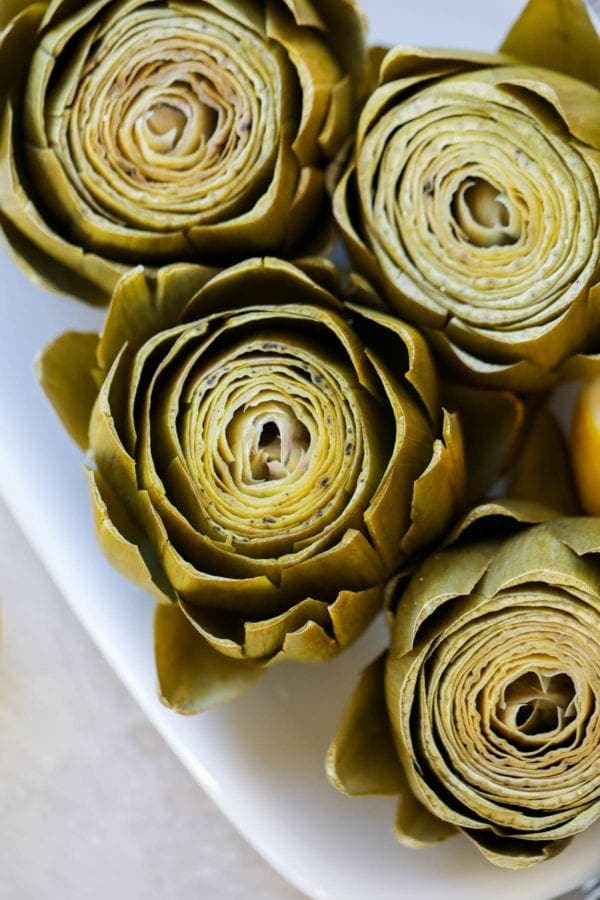 Freshly cooked artichokes on a white platter