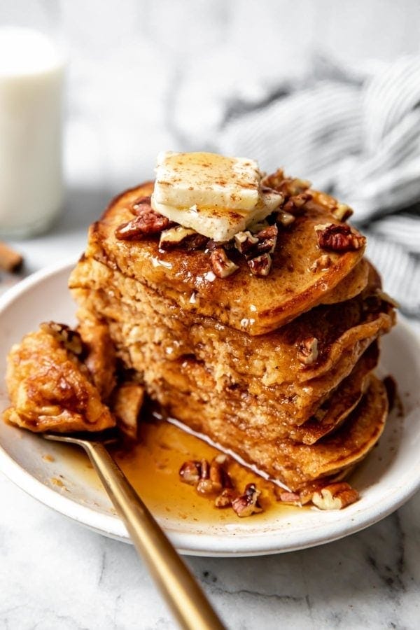 A stack of gluten free fluffy sweet potato pancakes cut in half to show the fluffy inside texture.