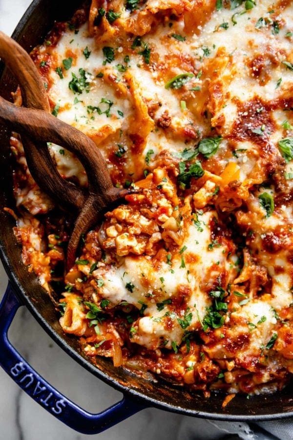 A close up of Easy Skillet Lasagna with a serving spoon scooping up a hefty portion of creamy and cheesy lasagna
