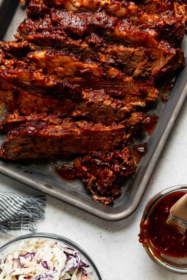 Close up of easy Instant Pot Brisket sliced thinly in a deep baking sheet