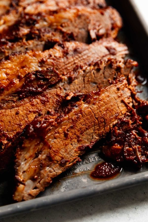 A close up view of a thin slice of juicy barbecue beef brisket on a silver baking tray