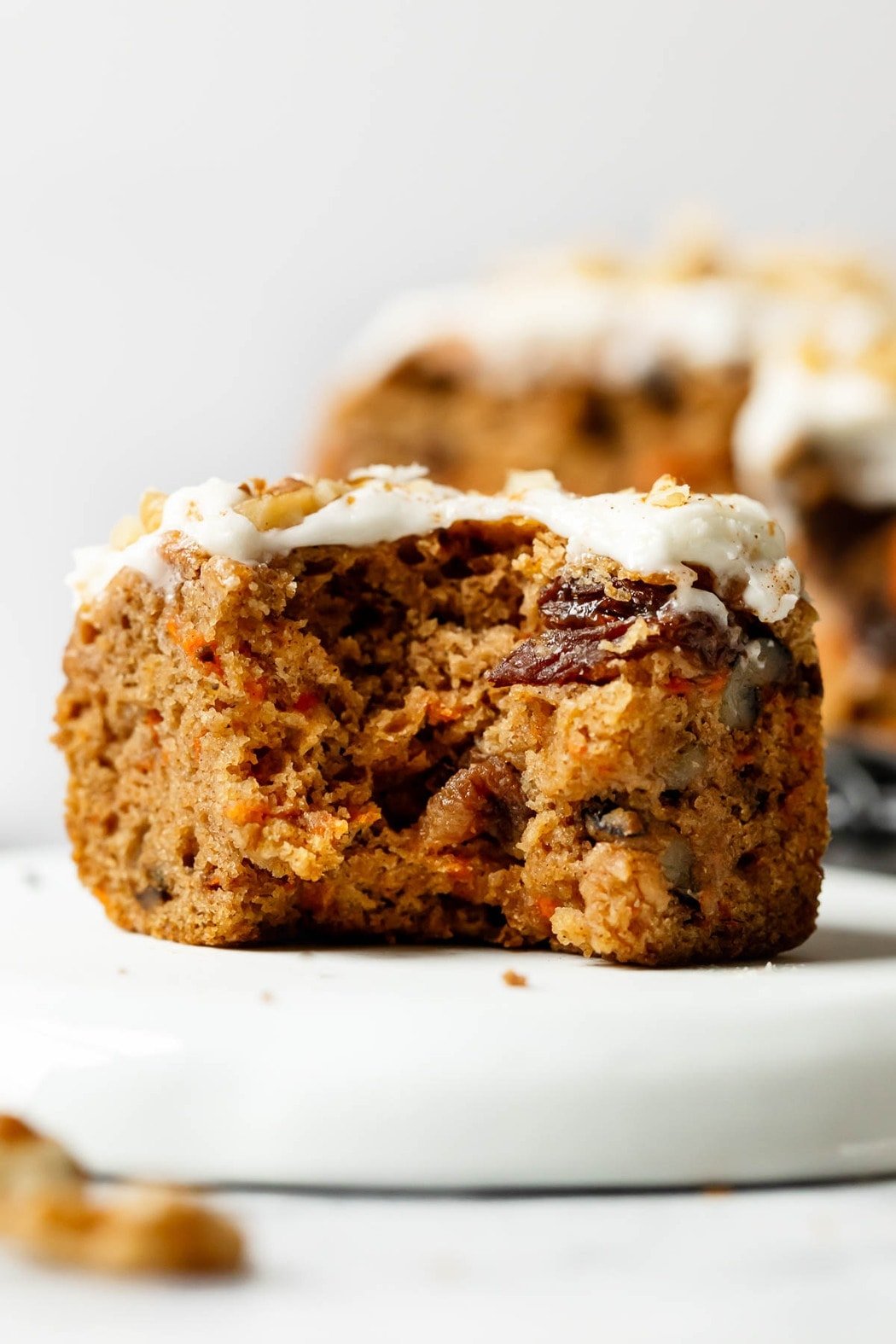 A close up view of a gluten-free carrot cake bar with a bite taken out to show texture