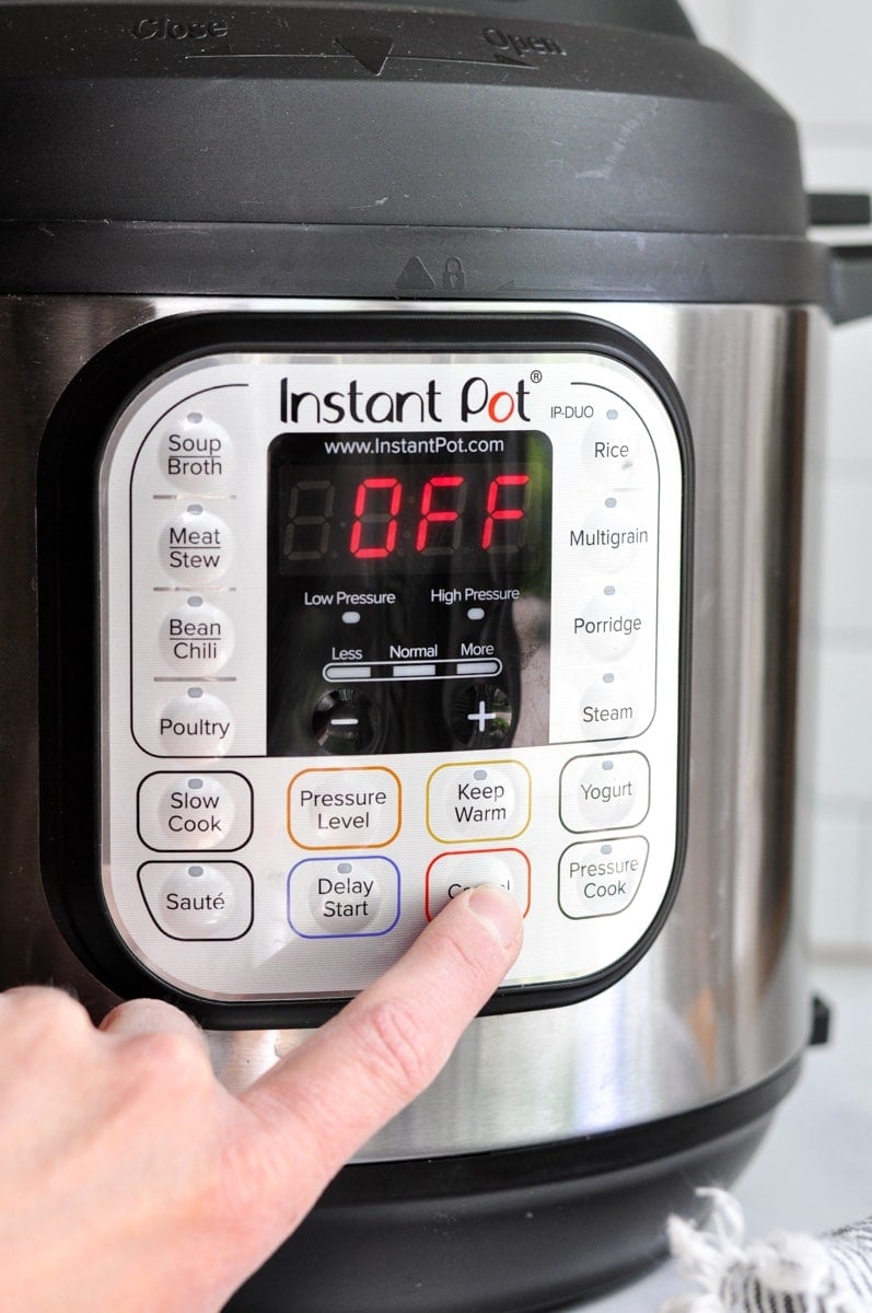 A hand turning off an instant pot