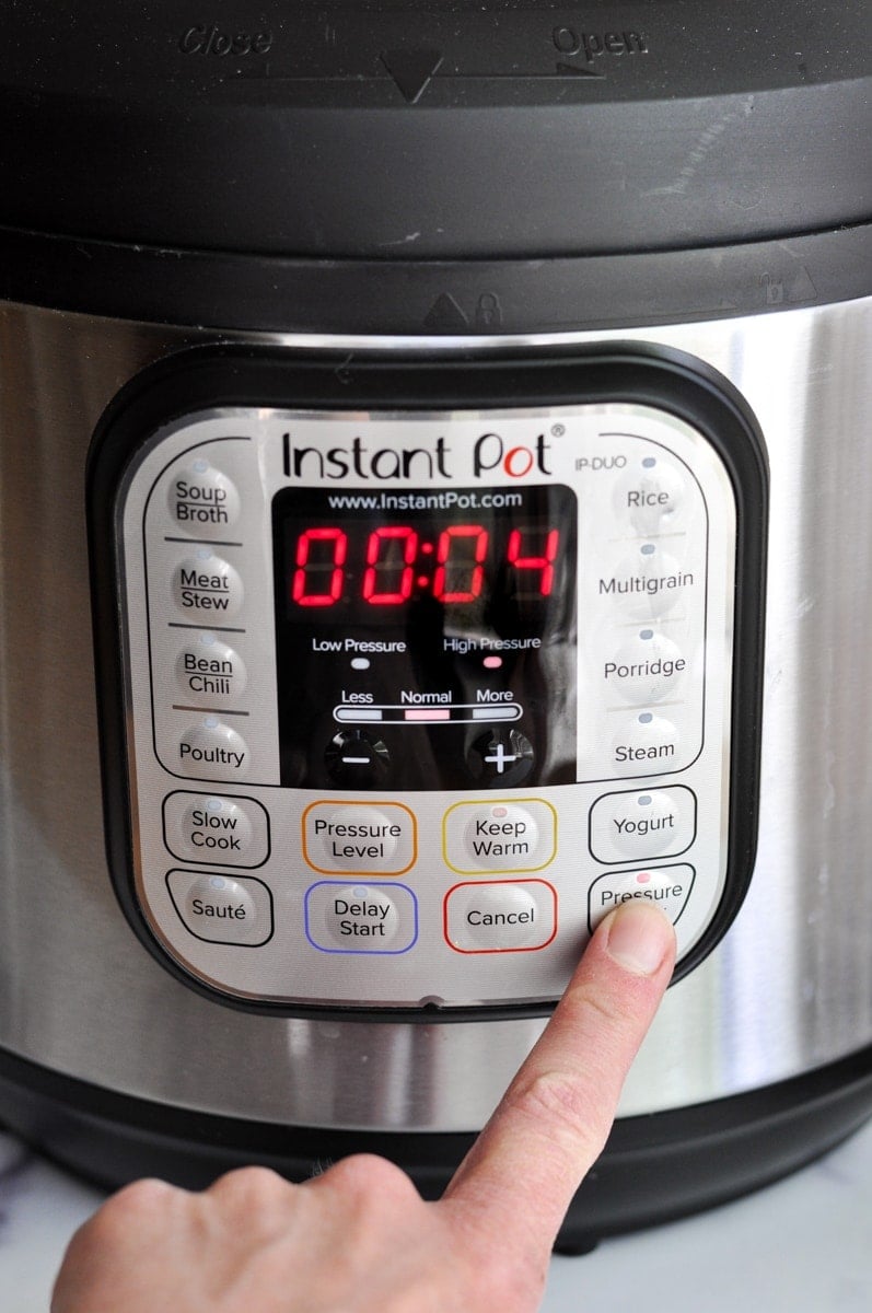 A hand setting a timer on an instant pot