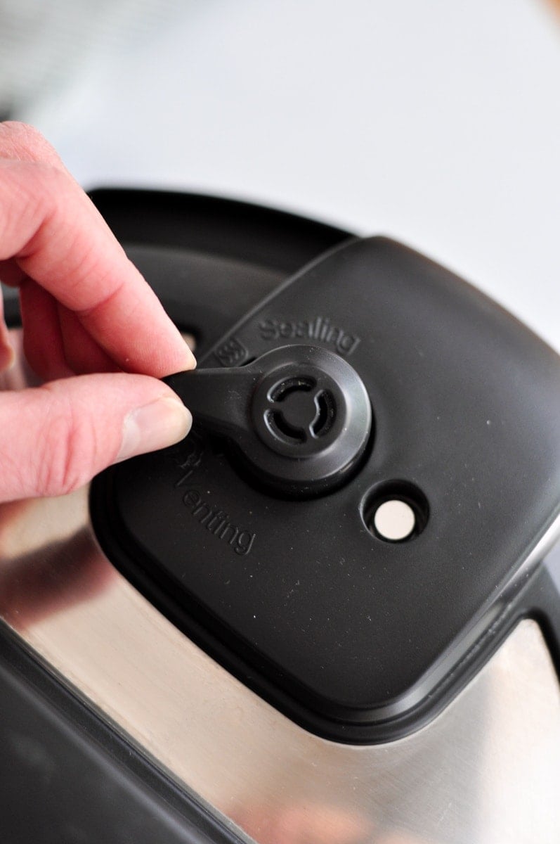 a hand releasing the steam pressure of the instant pot