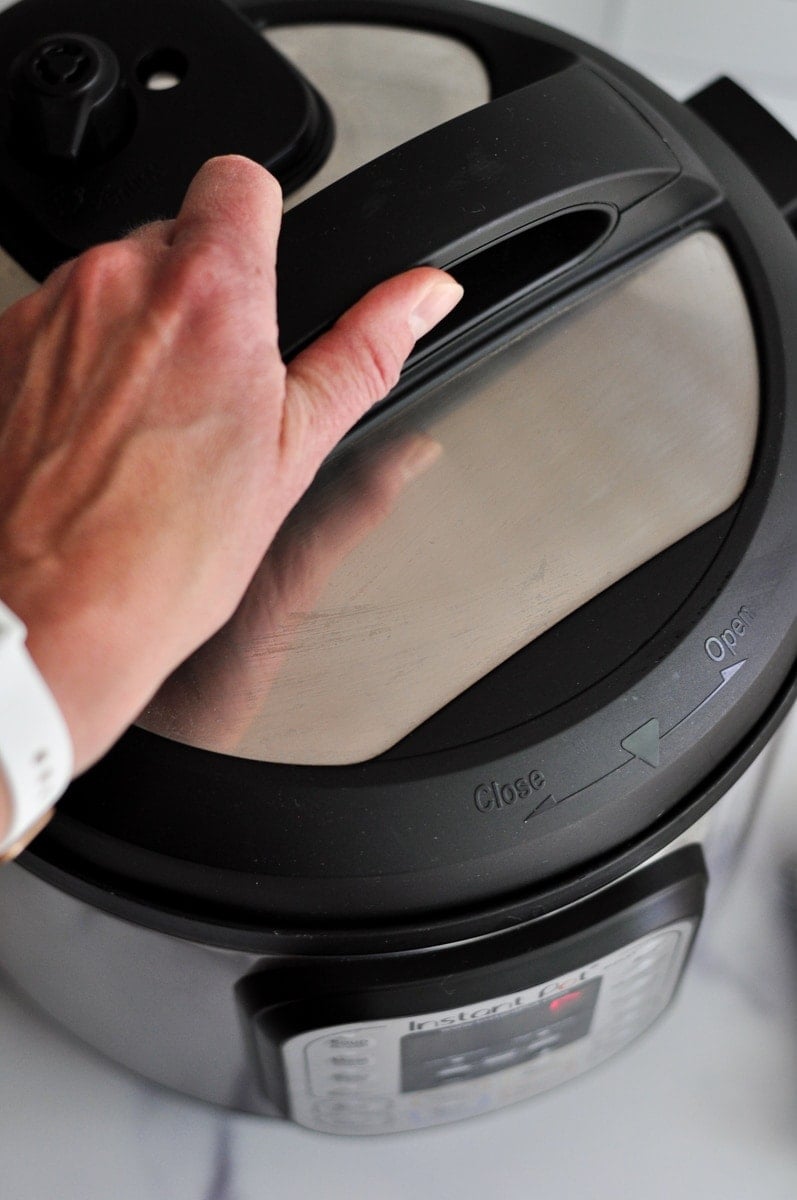 A hand locking the lid of an instant pot