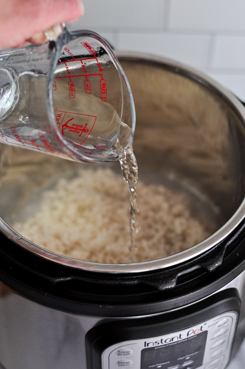 A hand pouring water into an instant pot