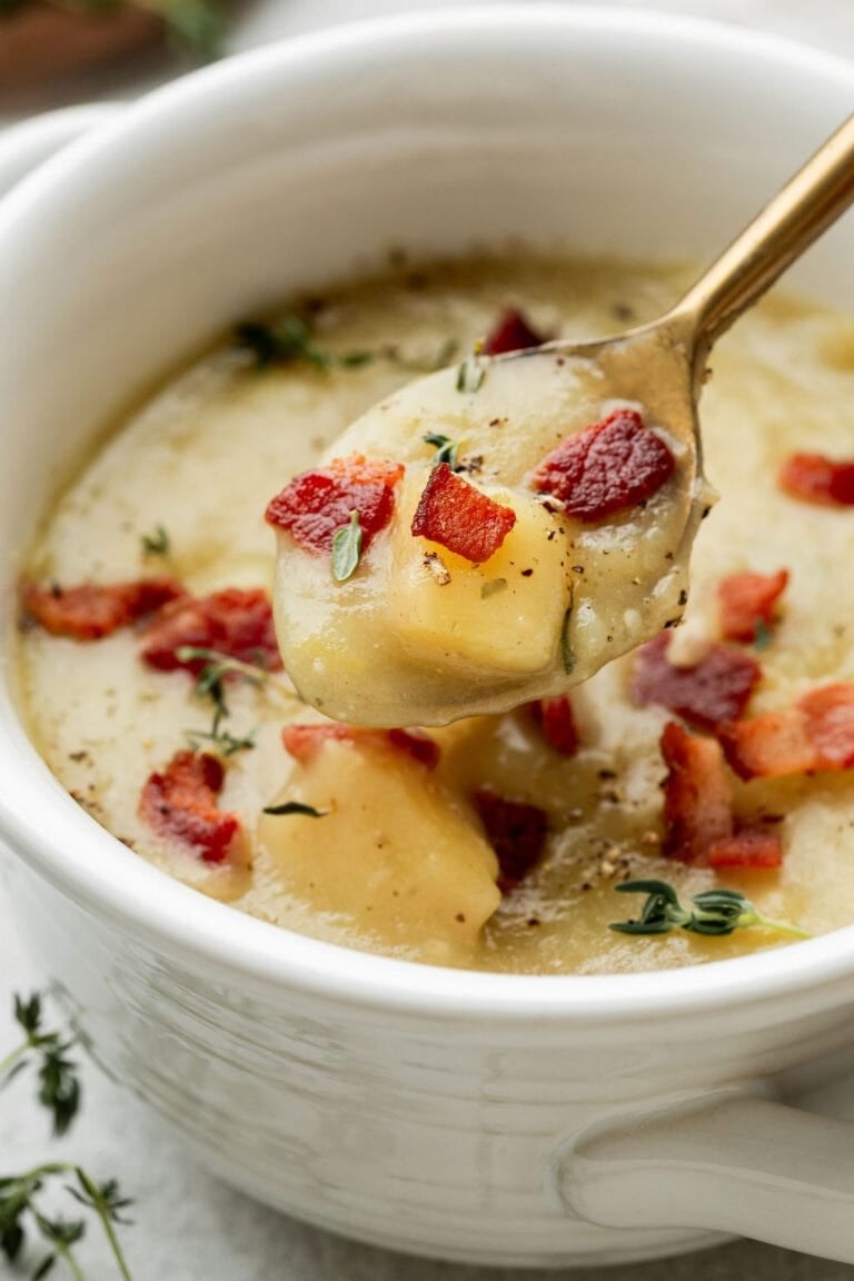 Close up view of a bowl of creamy potato leek soup with bacon crumbles on top.