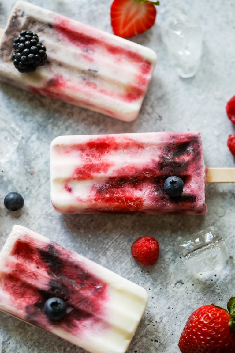 Overhead view of Creamy Yogurt Popsicles with Berries on a marble countertop.
