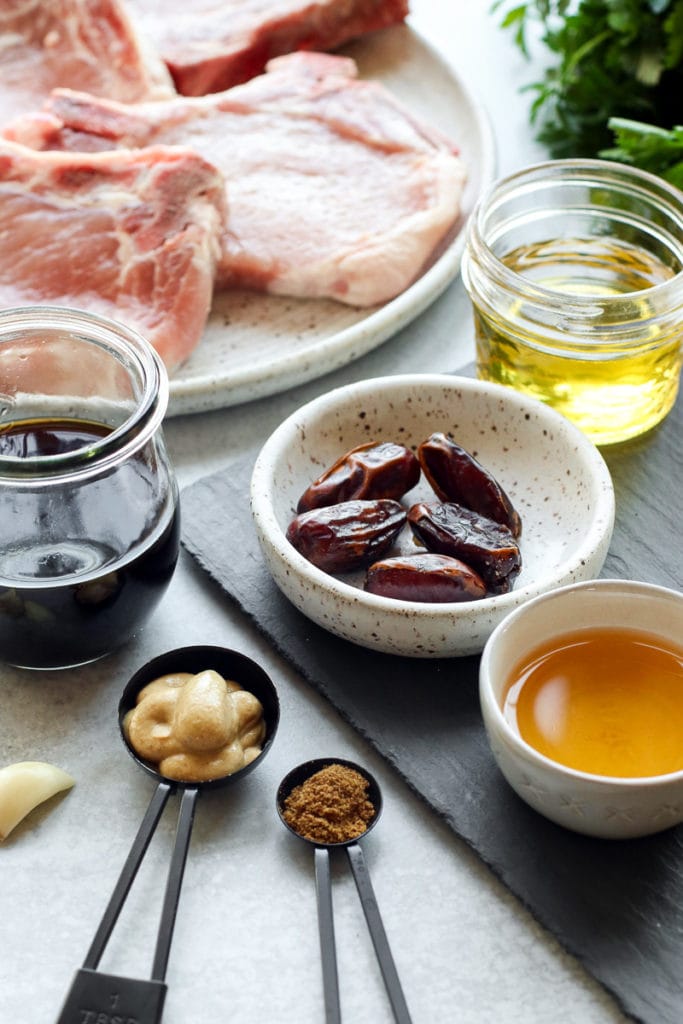 All ingredients for the pork chop marinade in measuring spoons, bowls, and small jars. 