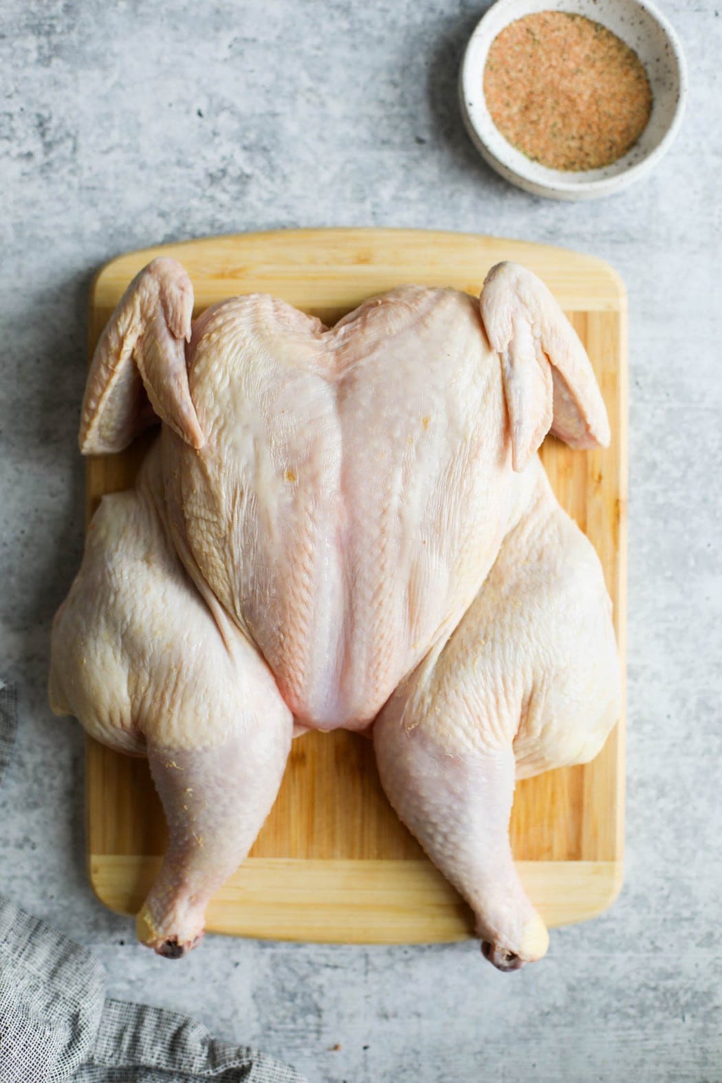 A raw whole chicken on a wooden cutting board