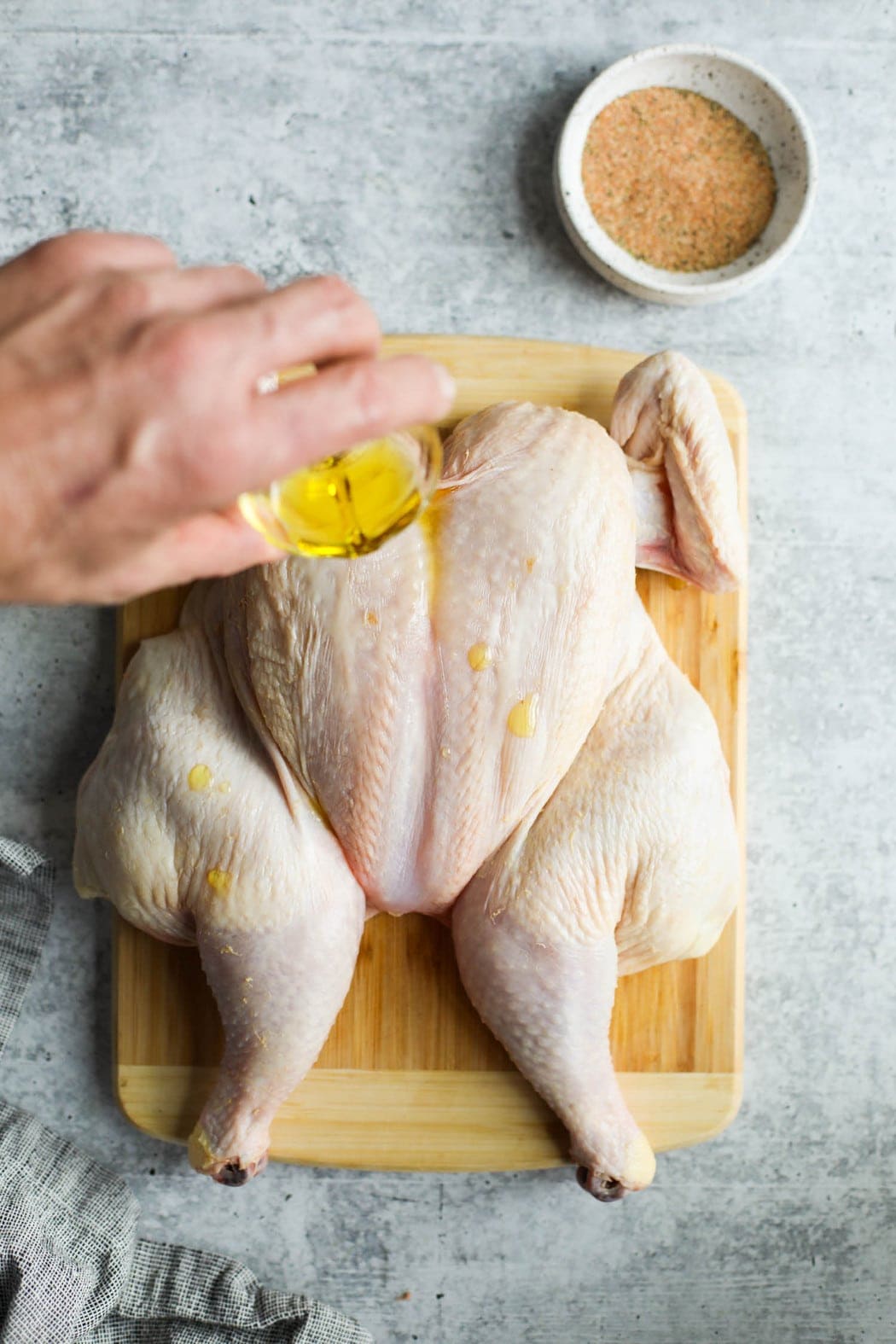 Olive oil being drizzled over a whole chicken