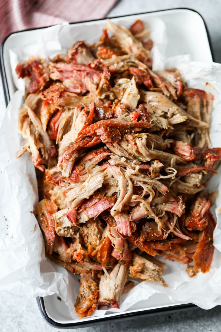 Overhead view of a rectangular dish filled with shredded smoked pork butt showing the tender texture. 