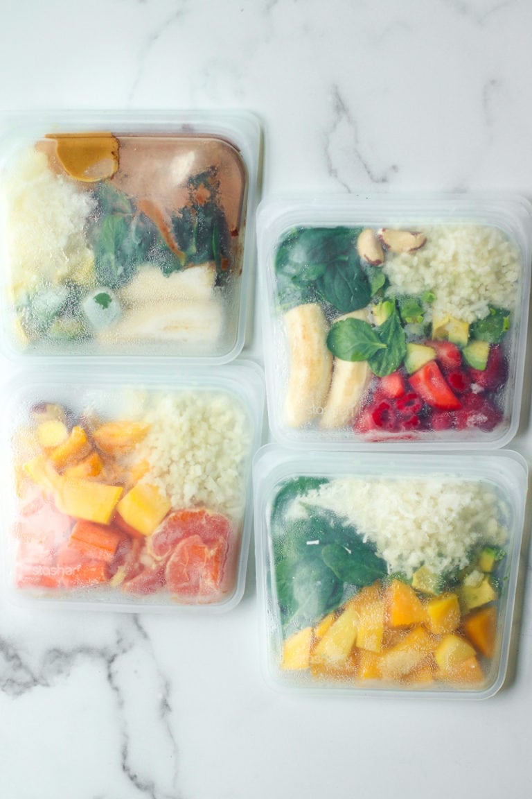 Overhead view of 4 freezer packs of smoothie ingredients including fruits and vegetables.