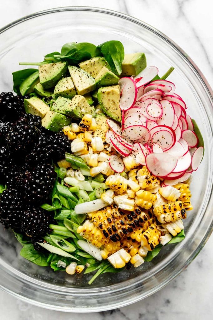 All ingredients for grilled corn salad in a glass mixing bowl.
