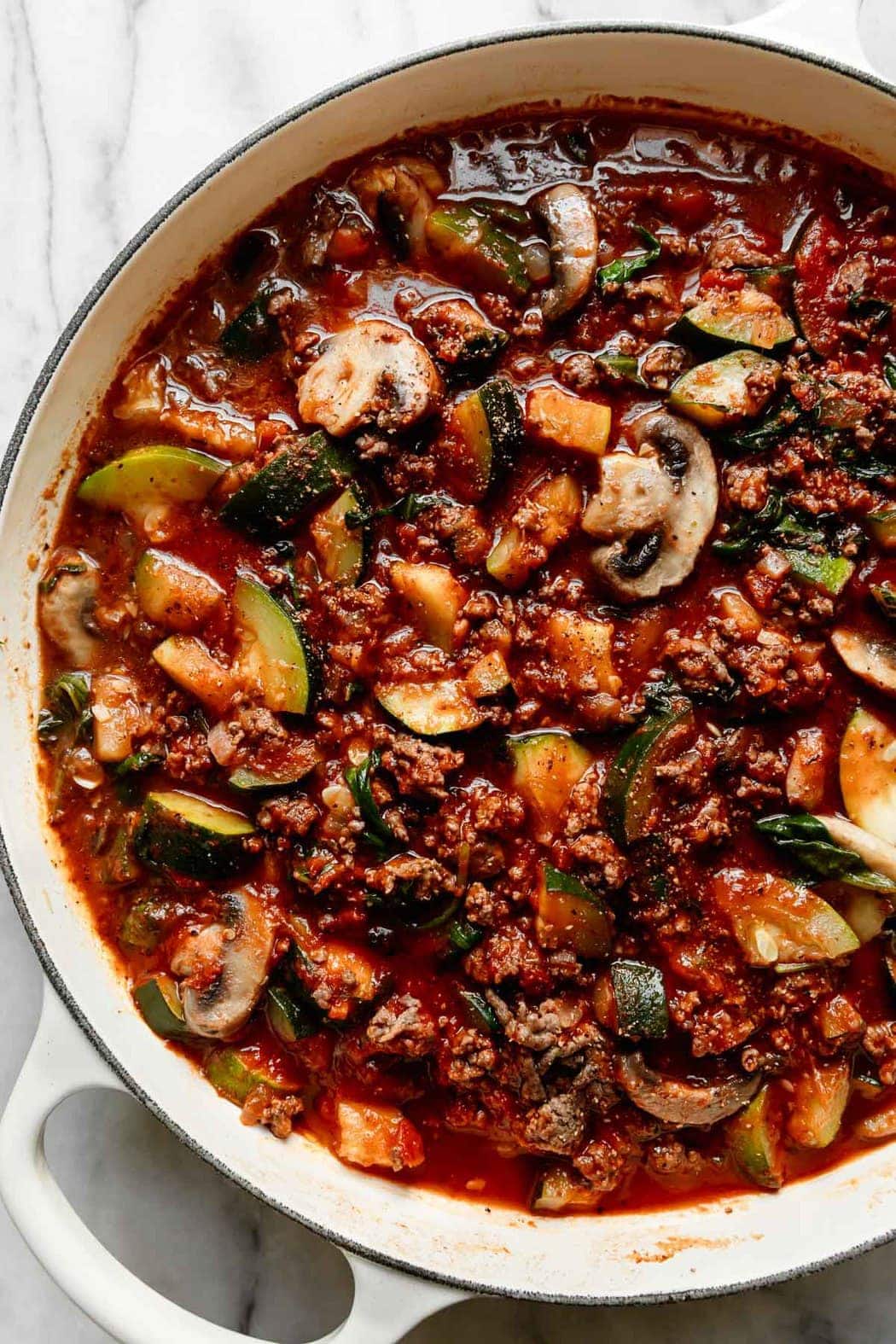 Overhead view of the beef and veggie filling for one-skillet zucchini lasagna in white skillet
