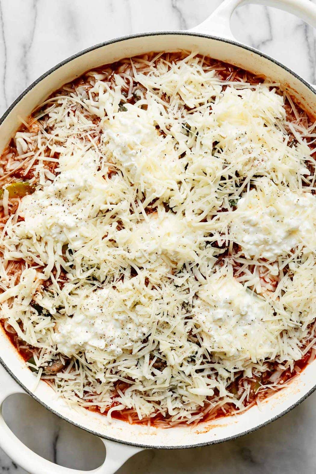 One-skillet zucchini lasagna freshly topped with mozzarella and parmesan cheese ready to start cooking.