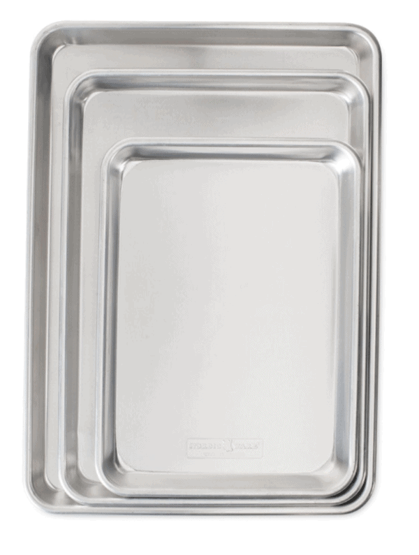 Three silver baking sheets nestled into each other on white background