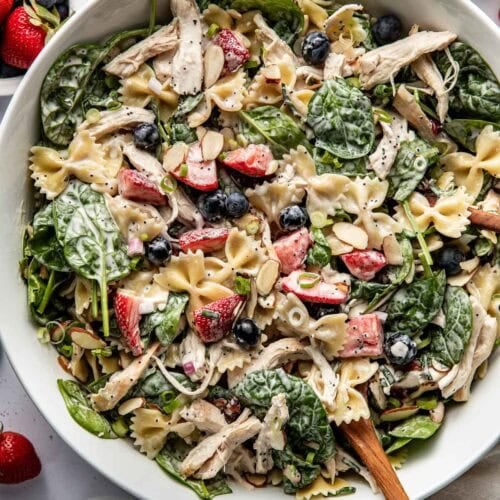 Summer pasta salad with fresh berries, shredded chicken and spinach in a large serving bowl