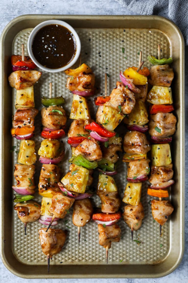 Overhead view of a sheet pan of colorful freshly grilled chicken pineapple skewers 