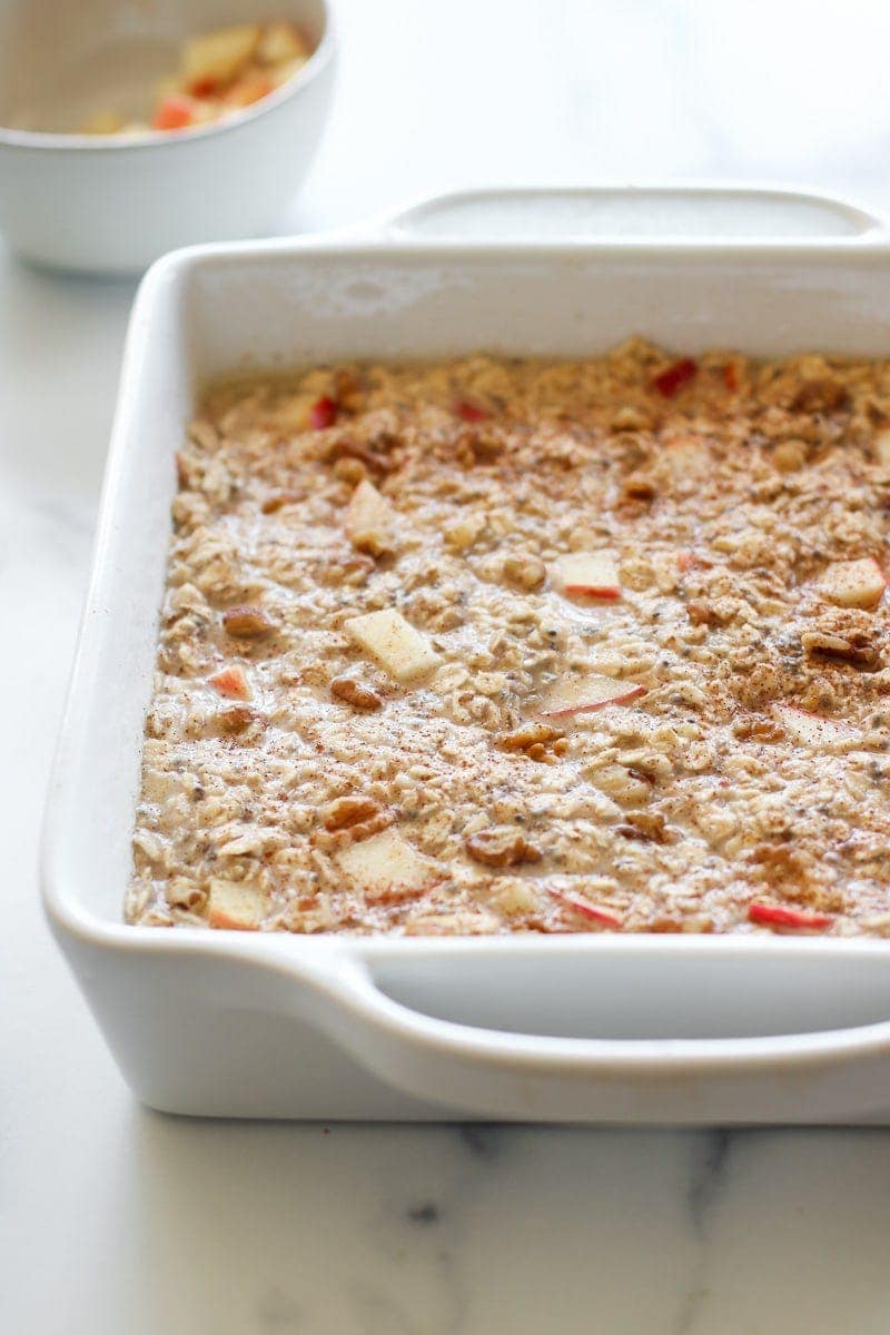 Overhead view of a white baking dish filled with Baked Apple Cinnamon Oatmeal batter 