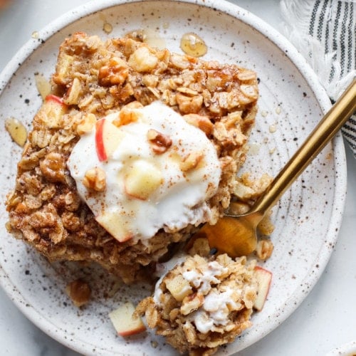 Serving of apple cinnamon baked oatmeal on plate topped with yogurt and apple chunks