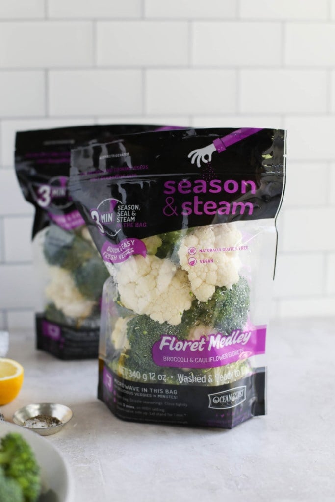 Two bags of broccoli and cauliflower steam bags standing upright on a counter.