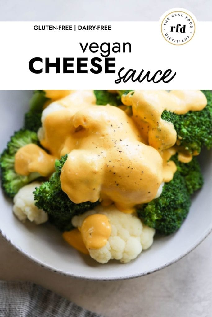 Close up view of vegan cheese sauce coating steamed broccoli and cauliflower in a small bowl.