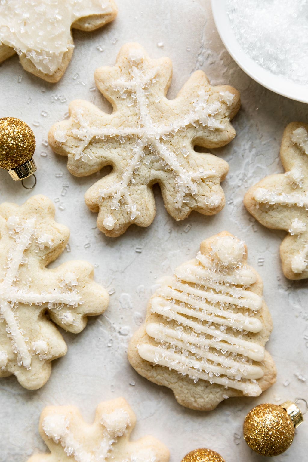 Close up view of gluten-free sugar cookie cut-out in the shape of a snowflake with white piping and shimmering white crystals as decoration.