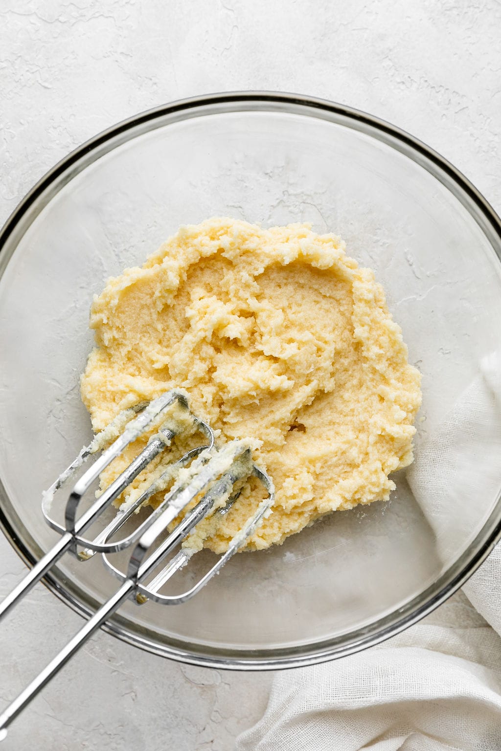 Overhead view of a glass bowl filled with sugar cookie dough with mixing beaters in the bowl