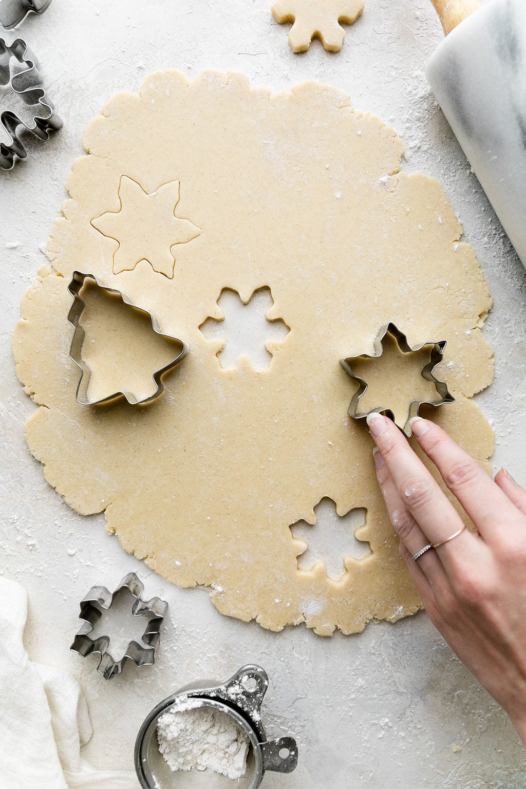 Gluten-free sugar cookie dough rolled out with cookie cutters pressing into the dough.