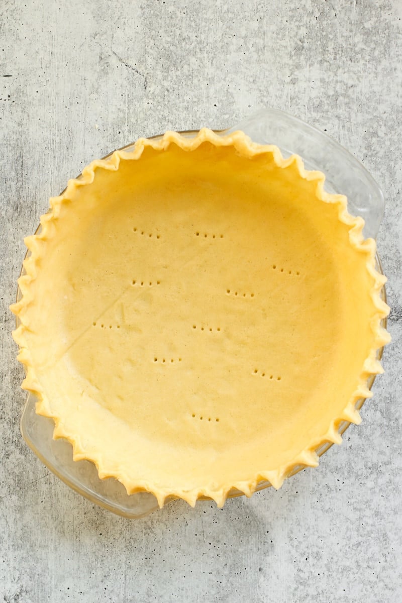 Overhead view of a gluten-free pie crust in a pie plate with fluted edges.