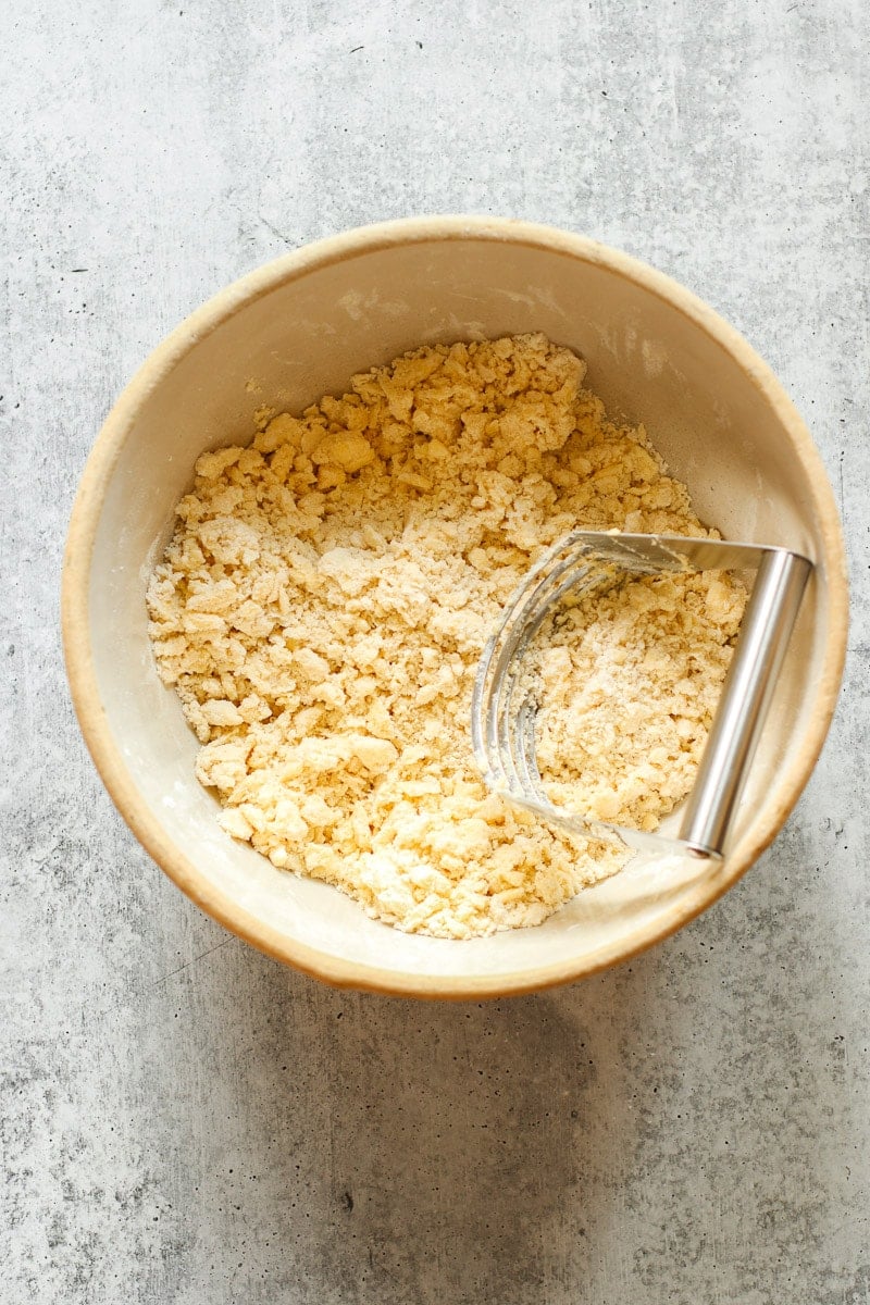 Butter cut into gluten-free flour in a mixing bowl with a pastry cutter in the mixture.