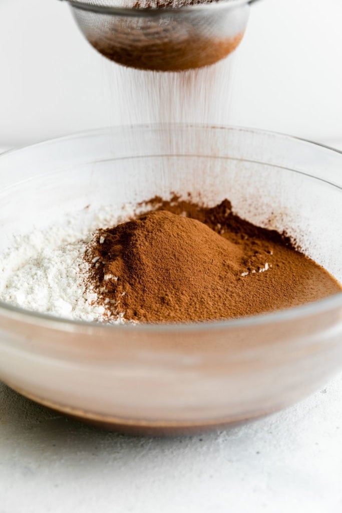 Cocoa being sifted into peppermint brownie cookie batter.