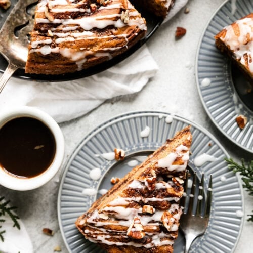 Overhead view several slices of cinnamon roll coffee cake plated on blue plates