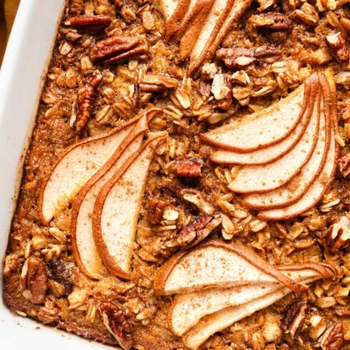 Overhead view of a square baking dish filled with freshly baked Gingerbread Baked Oatmeal topped with thinly sliced pears.
