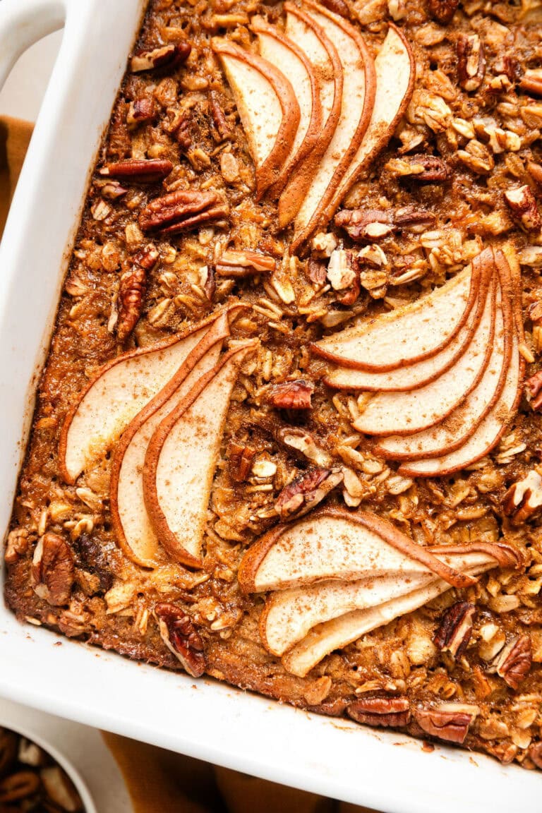 Overhead view of a square baking dish filled with freshly baked Gingerbread Baked Oatmeal topped with thinly sliced pears.