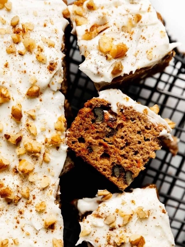 Overhead view of carrot cake bars topped with cream cheese frosting and pecan pieces.