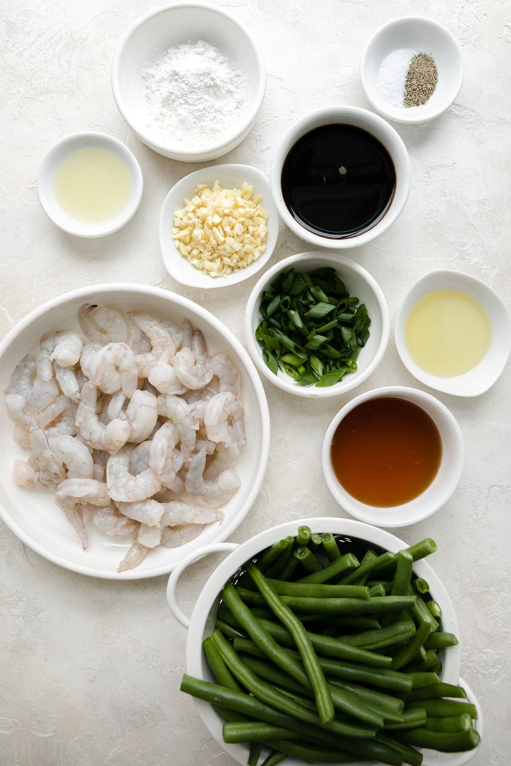 Overhead view of a variety of ingredients for Sheet Pan Honey Garlic Shrimp Dinner in different sized bowls