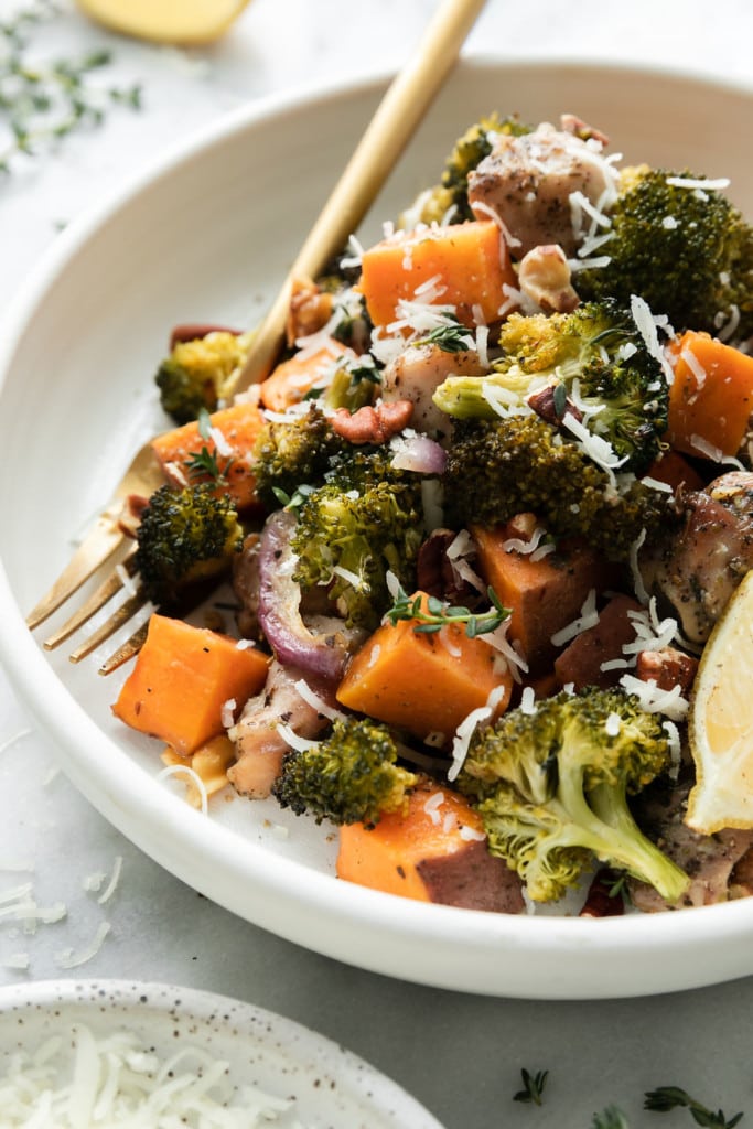 Close up view of sweet potato chicken broccoli bake on a white plate topped with toasted walnuts and mozzarella cheese shreds.