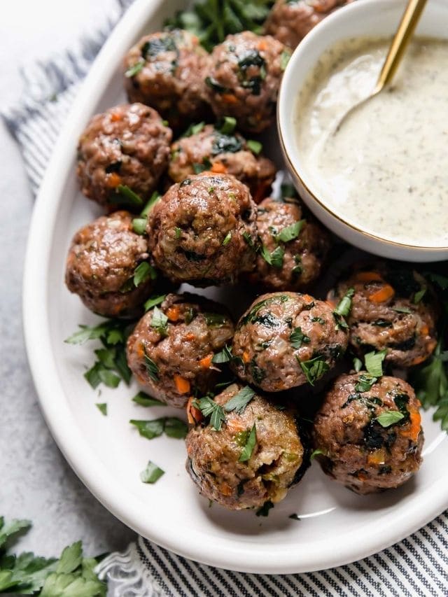 Close up view of ultimate meal prep meatballs on a white platter with a bowl of ranch on the side.